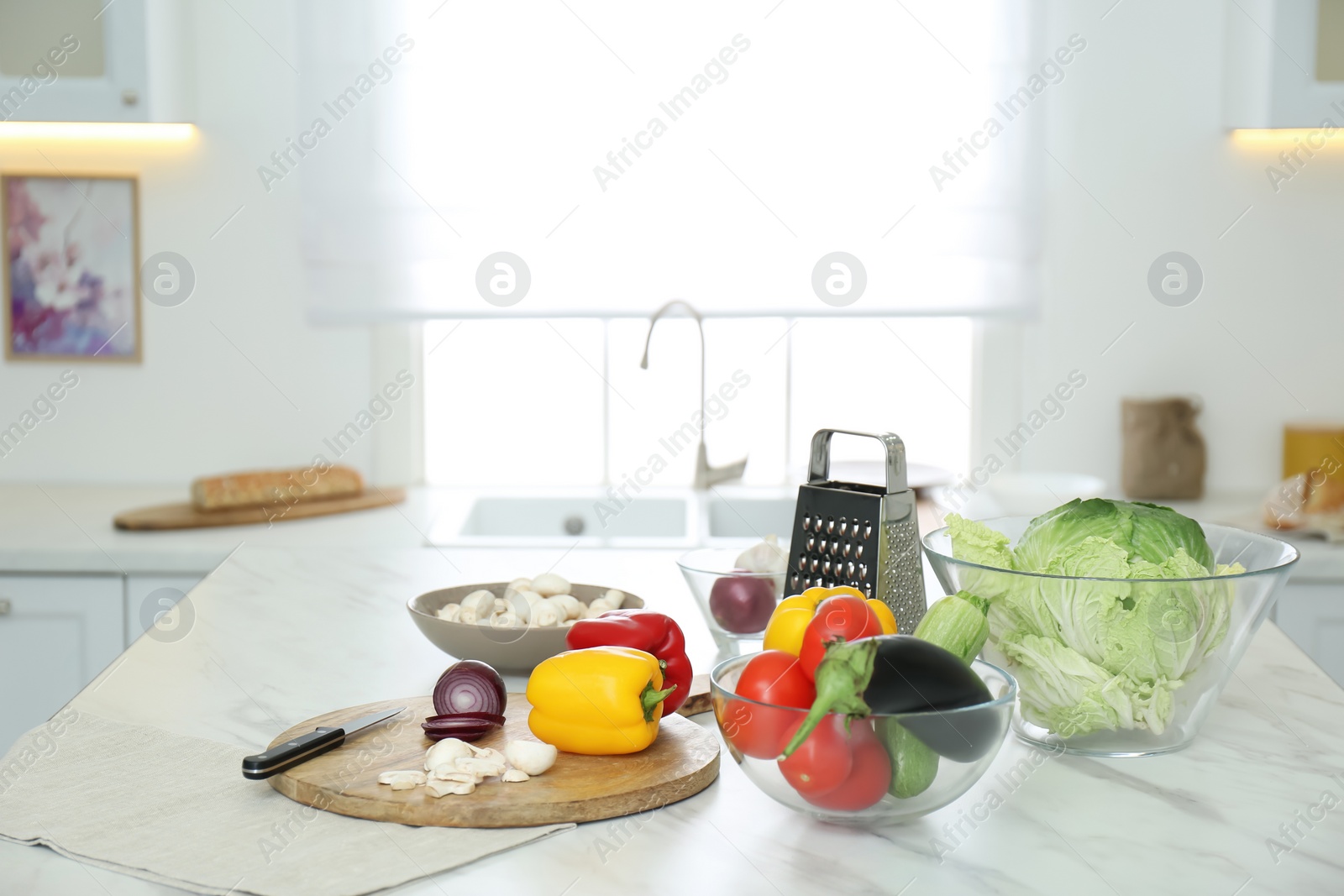 Photo of Different fresh vegetables and mushrooms on white table in modern kitchen. Space for text