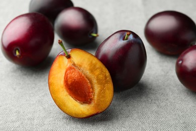 Photo of Many tasty ripe plums on light fabric, closeup