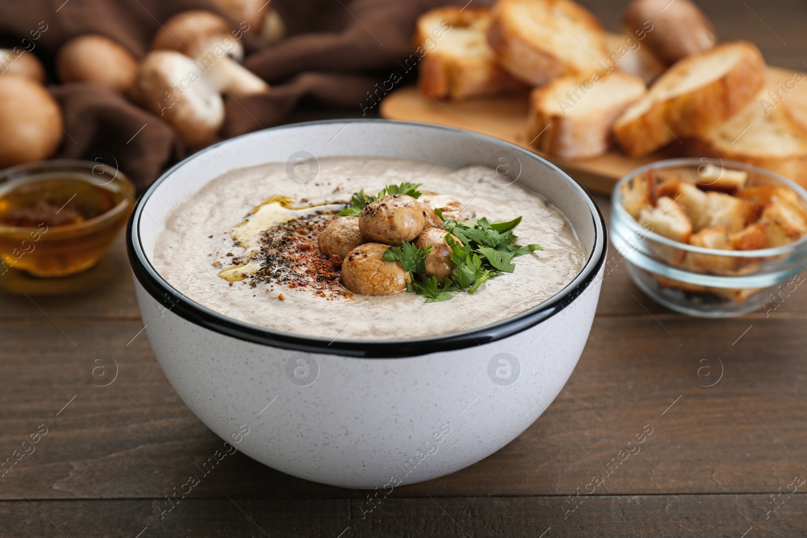 Photo of Delicious cream soup with mushrooms on wooden table