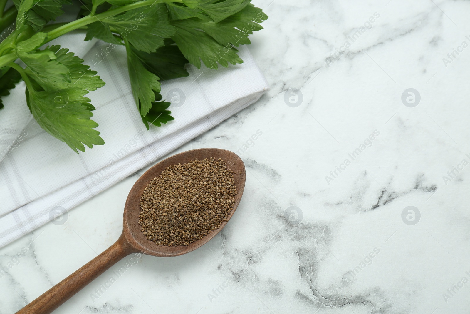 Photo of Spoon of celery seeds on white marble table, flat lay. Space for text