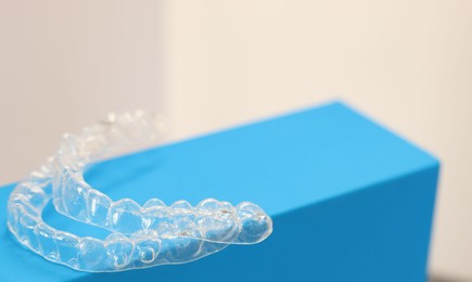 Photo of Transparent dental aligners on beige background, closeup. Space for text