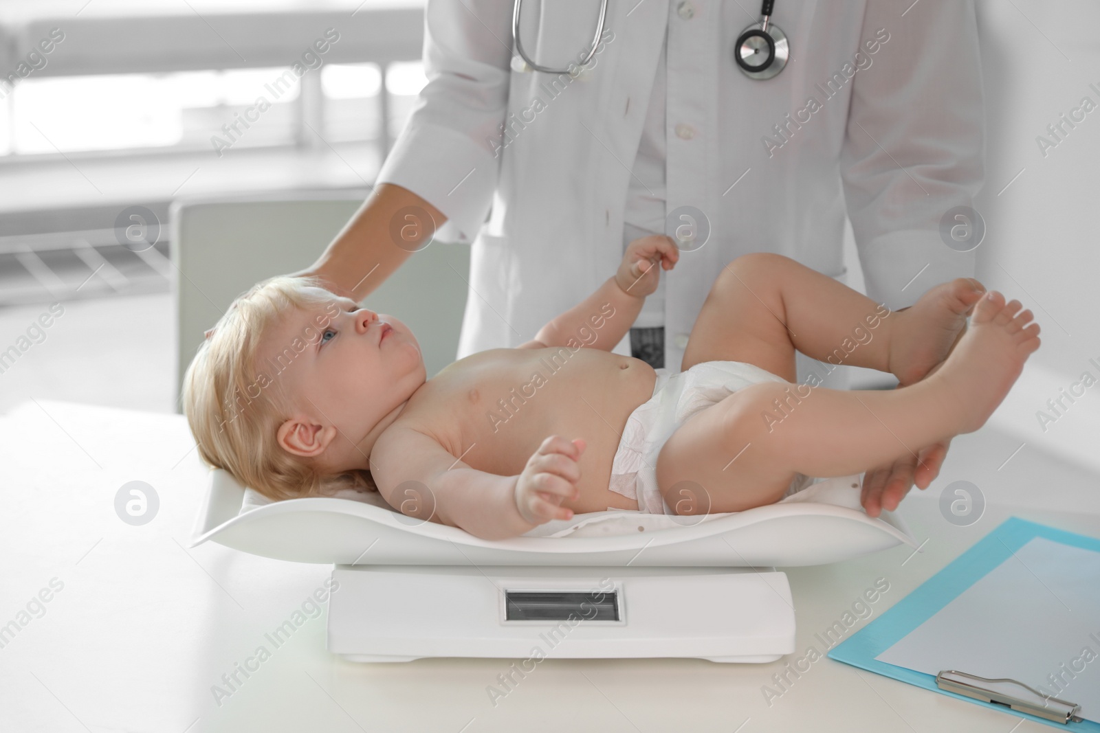 Photo of Pediatrician weighting baby on scale in hospital. Healthy growth