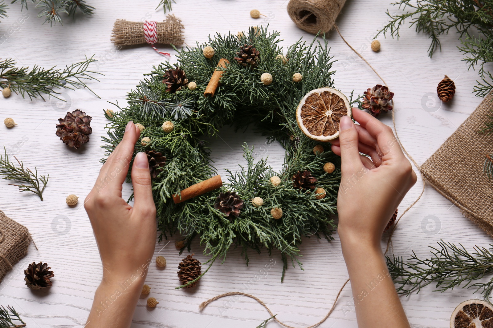 Photo of Florist making beautiful Christmas wreath at white wooden table, top view