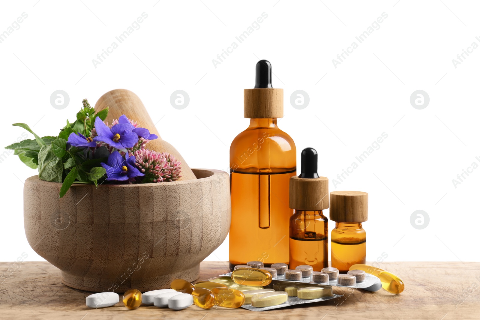 Photo of Mortar with fresh herbs, extracts and pills on white background