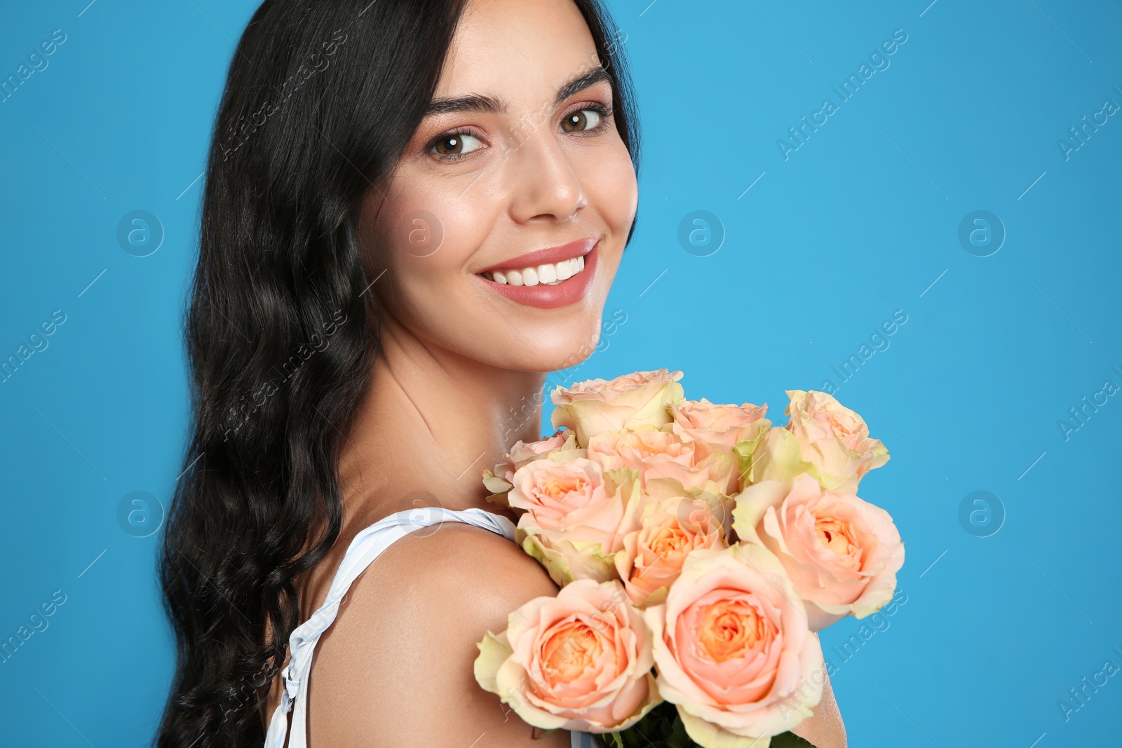 Photo of Portrait of smiling woman with beautiful bouquet on light blue background