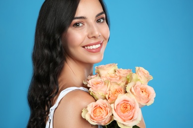 Photo of Portrait of smiling woman with beautiful bouquet on light blue background