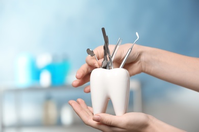 Dentist putting professional tool into tooth shaped holder in clinic, closeup