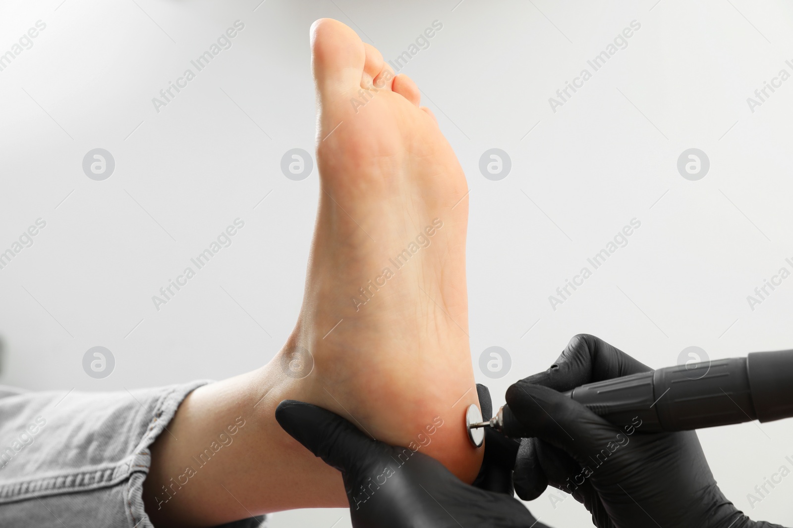 Photo of Professional master making hardware pedicure for client in beauty salon, closeup