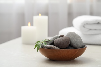 Spa stones in wooden bowl on white table indoors