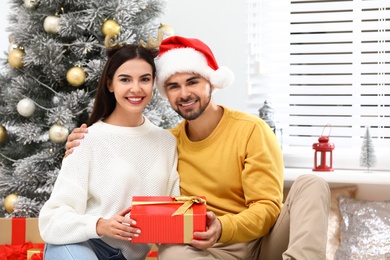 Happy young couple with Christmas gift at home