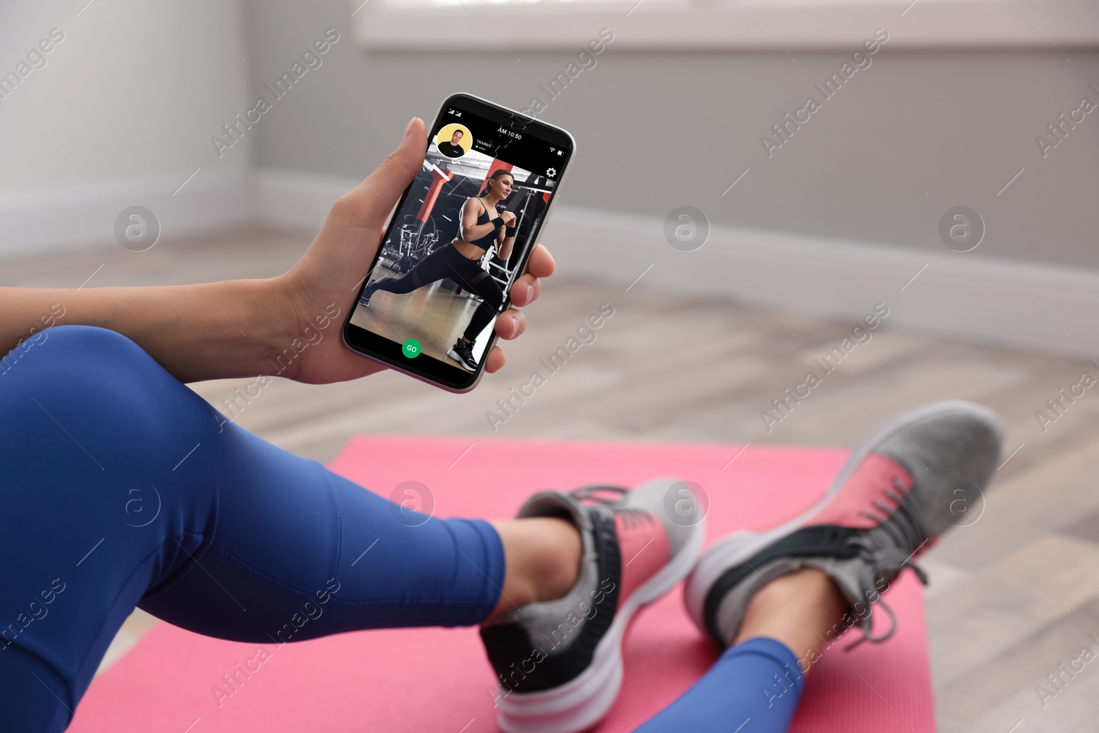 Image of Woman having workout with personal trainer via smartphone at home, closeup