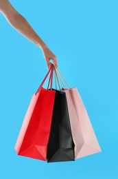 Photo of Woman with paper shopping bags on light blue background, closeup