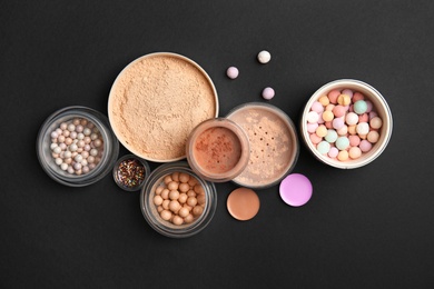 Flat lay composition with various makeup face powders on black background