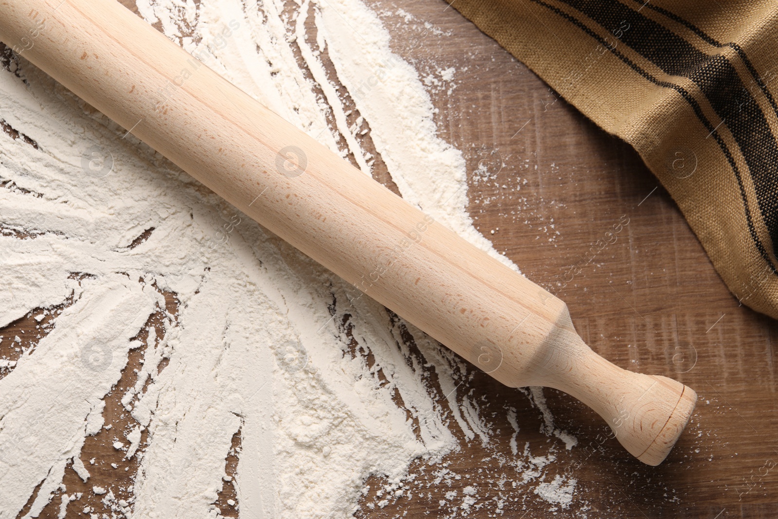 Photo of Scattered flour and rolling pin on wooden table, top view