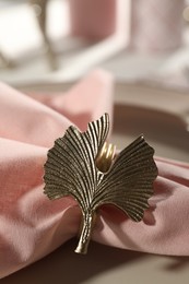Photo of Pink fabric napkin with beautiful decorative ring for table setting on plate, closeup