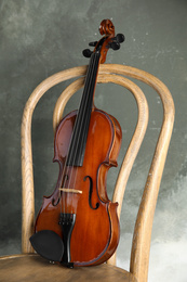Photo of Classic violin on chair against grey background