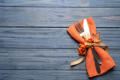 Photo of Cutlery with rowan berries on blue wooden table, top view with space for text. Thanksgiving Day celebration