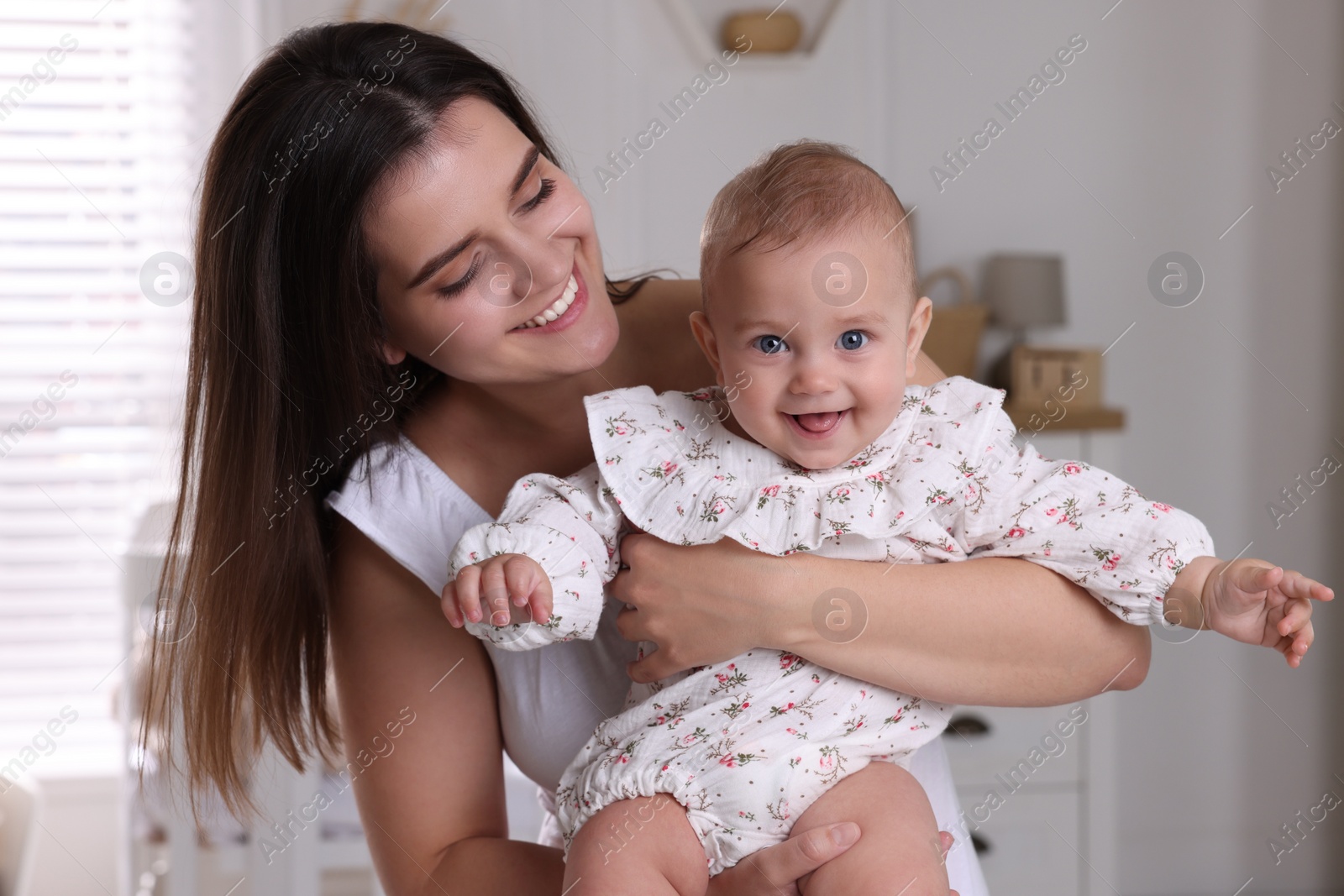 Photo of Happy young mother with her baby daughter in nursery