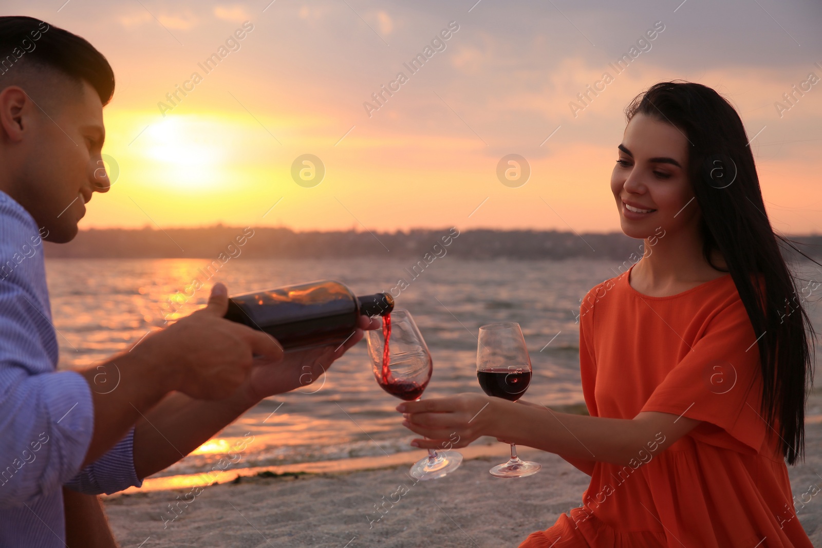 Photo of Lovely couple having picnic near river at sunset