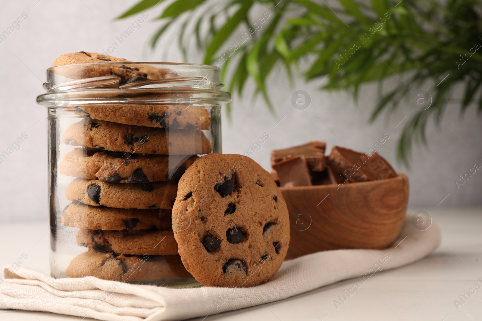 Photo of Glass jar with delicious chocolate chip cookies on white marble table