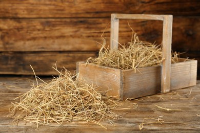 Photo of Heap of dried hay and crate on wooden table