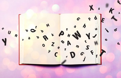 Image of Letters flying out from open book on lilac background, top view. Bokeh effect