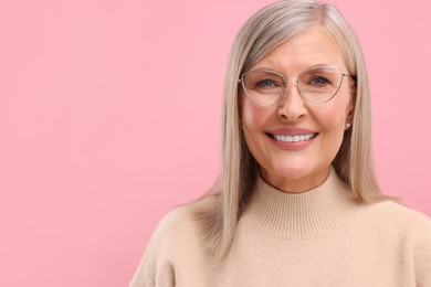 Photo of Portraitbeautiful middle aged woman in eyeglasses on pink background, space for text