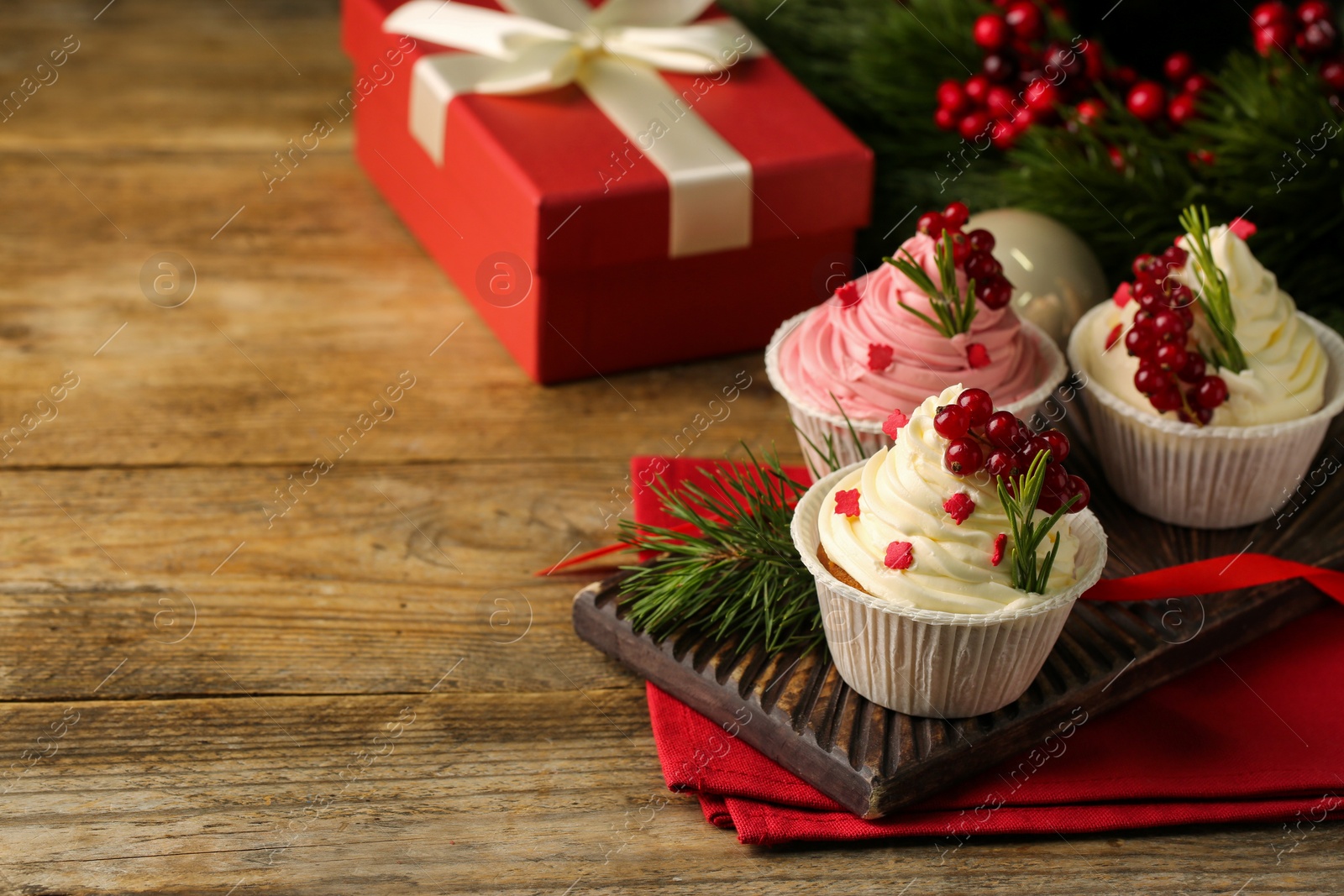 Photo of Delicious cupcakes and Christmas decorations on wooden table, space for text