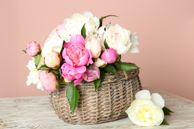 Basket with beautiful peonies on wooden table