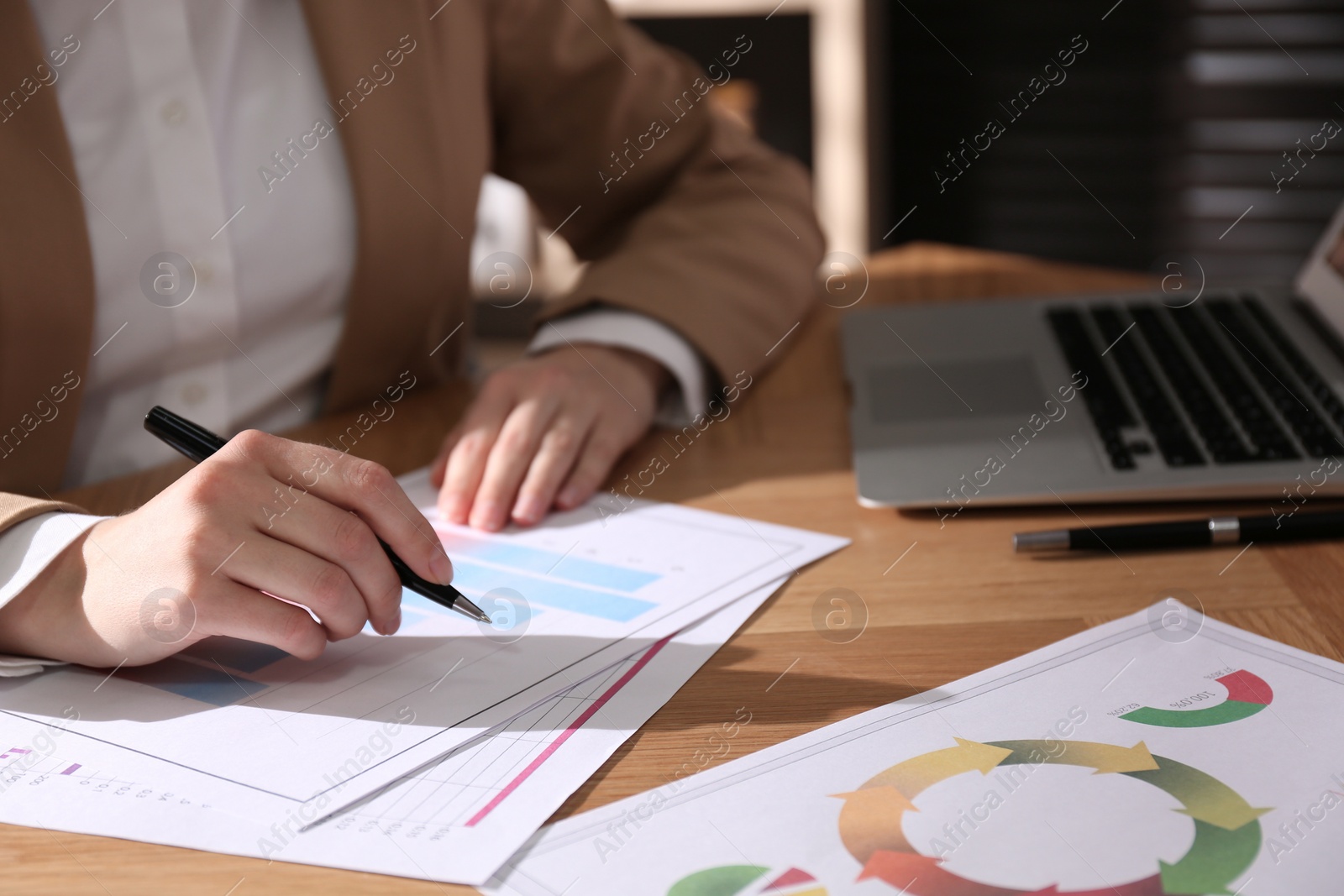 Photo of Businesswoman working with charts and graphs at table in office, closeup. Investment analysis