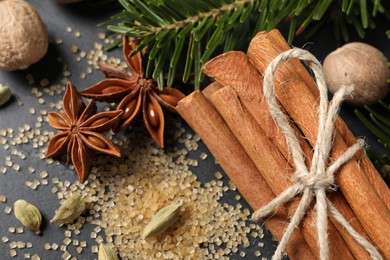 Different spices, nuts and fir branches on gray table, flat lay