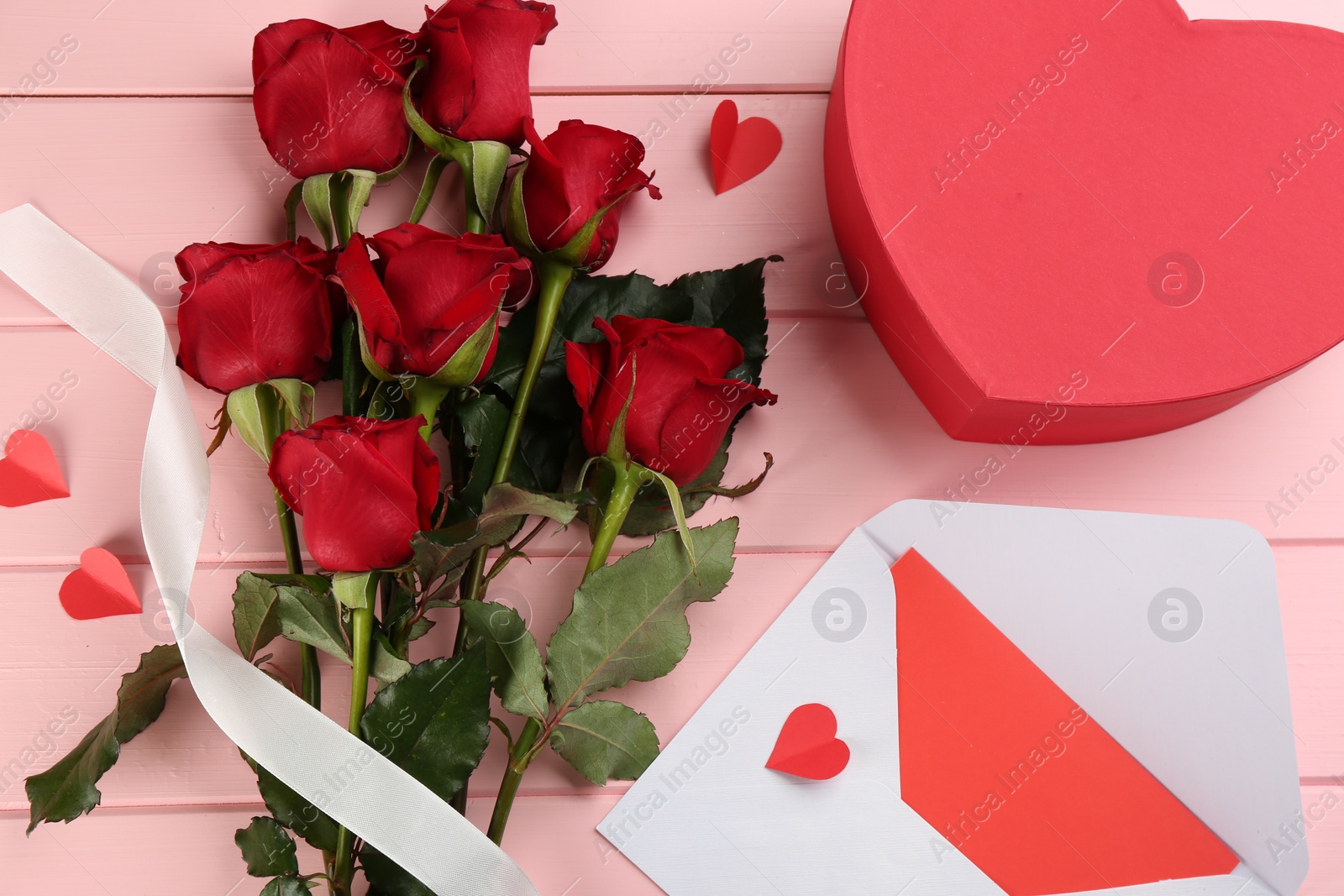 Photo of Flat lay composition with beautiful red roses on pink wooden background