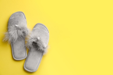 Photo of Pair of stylish soft slippers on yellow background, flat lay. Space for text
