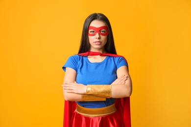 Photo of Confident young woman wearing superhero costume on orange background