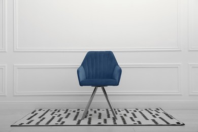 Modern blue armchair near white wall indoors