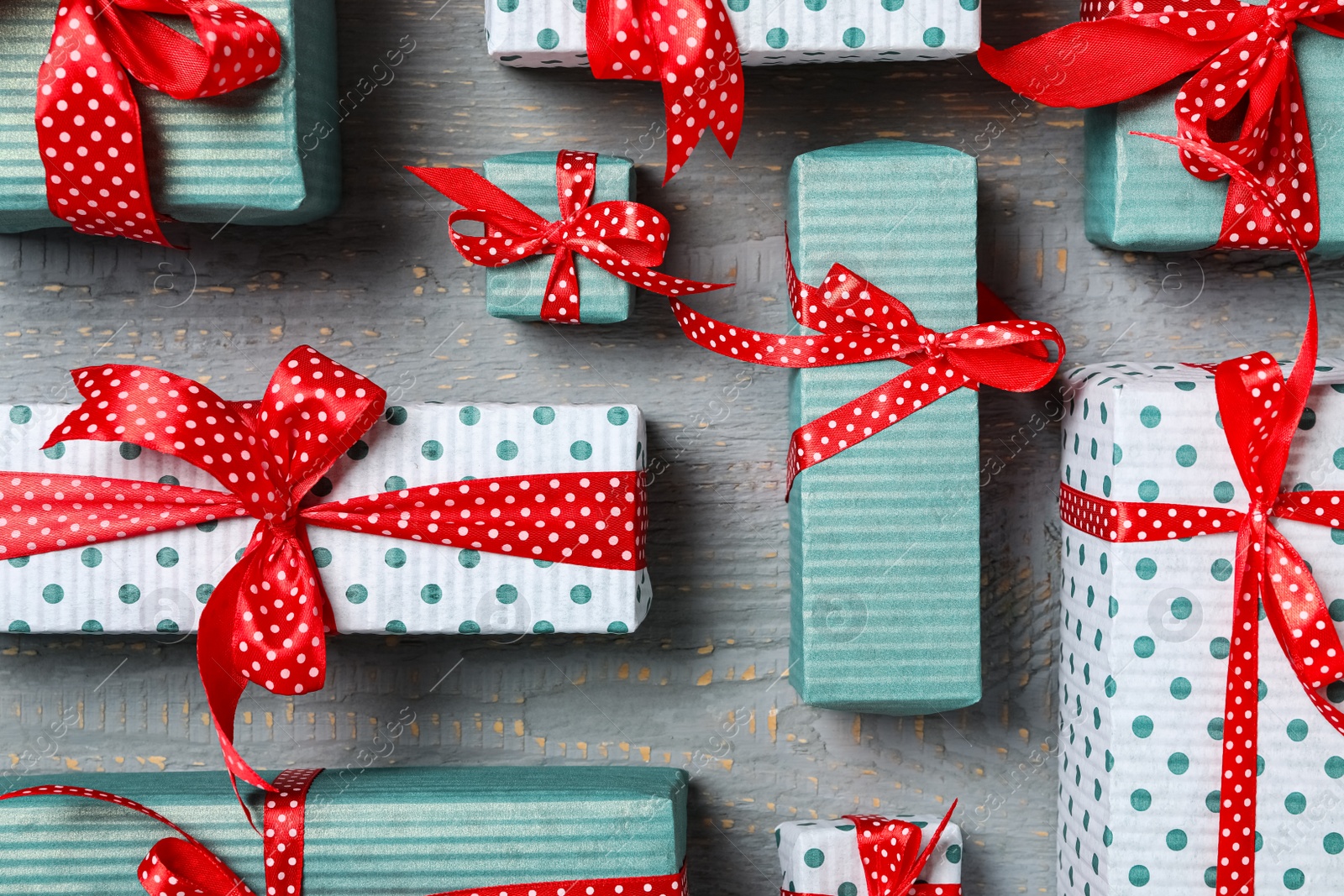 Photo of Christmas gift boxes with red bows on grey wooden background, flat lay