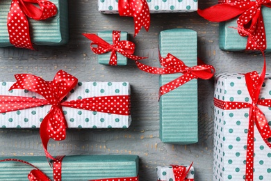 Christmas gift boxes with red bows on grey wooden background, flat lay