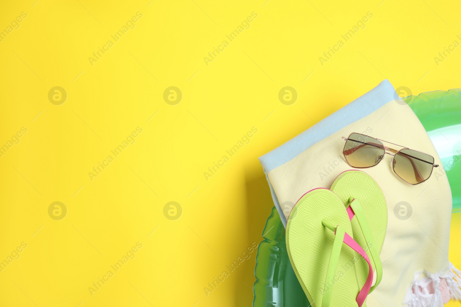 Photo of Beach accessories on yellow background, flat lay. Space for text