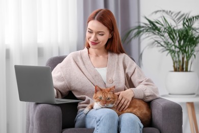 Photo of Woman with cat working in armchair at home