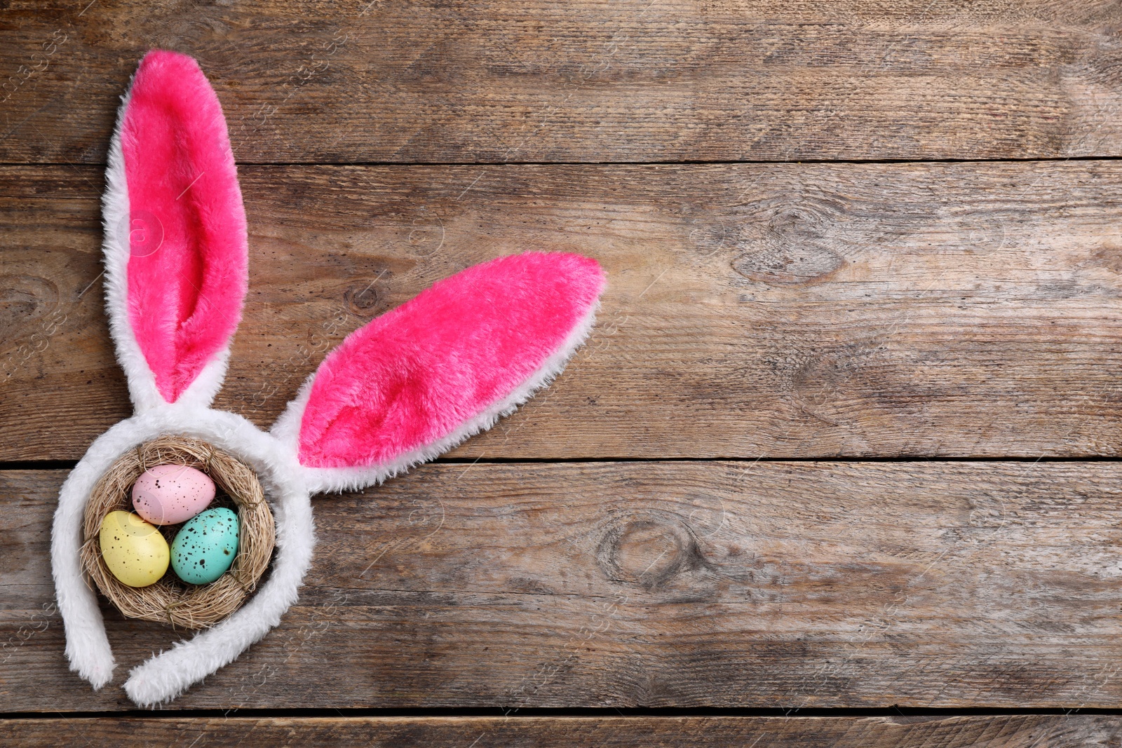 Photo of Headband with bunny ears, painted eggs and space for text on wooden background, flat lay. Easter holiday