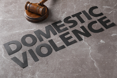 Photo of Words DOMESTIC VIOLENCE and gavel on grey marble table