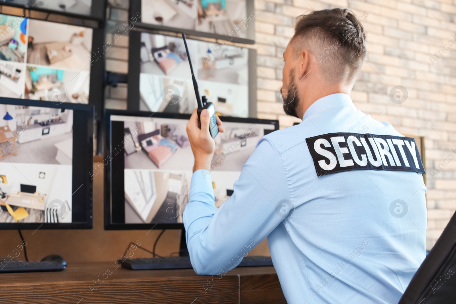 Photo of Male security guard with portable transmitter monitoring modern CCTV cameras indoors