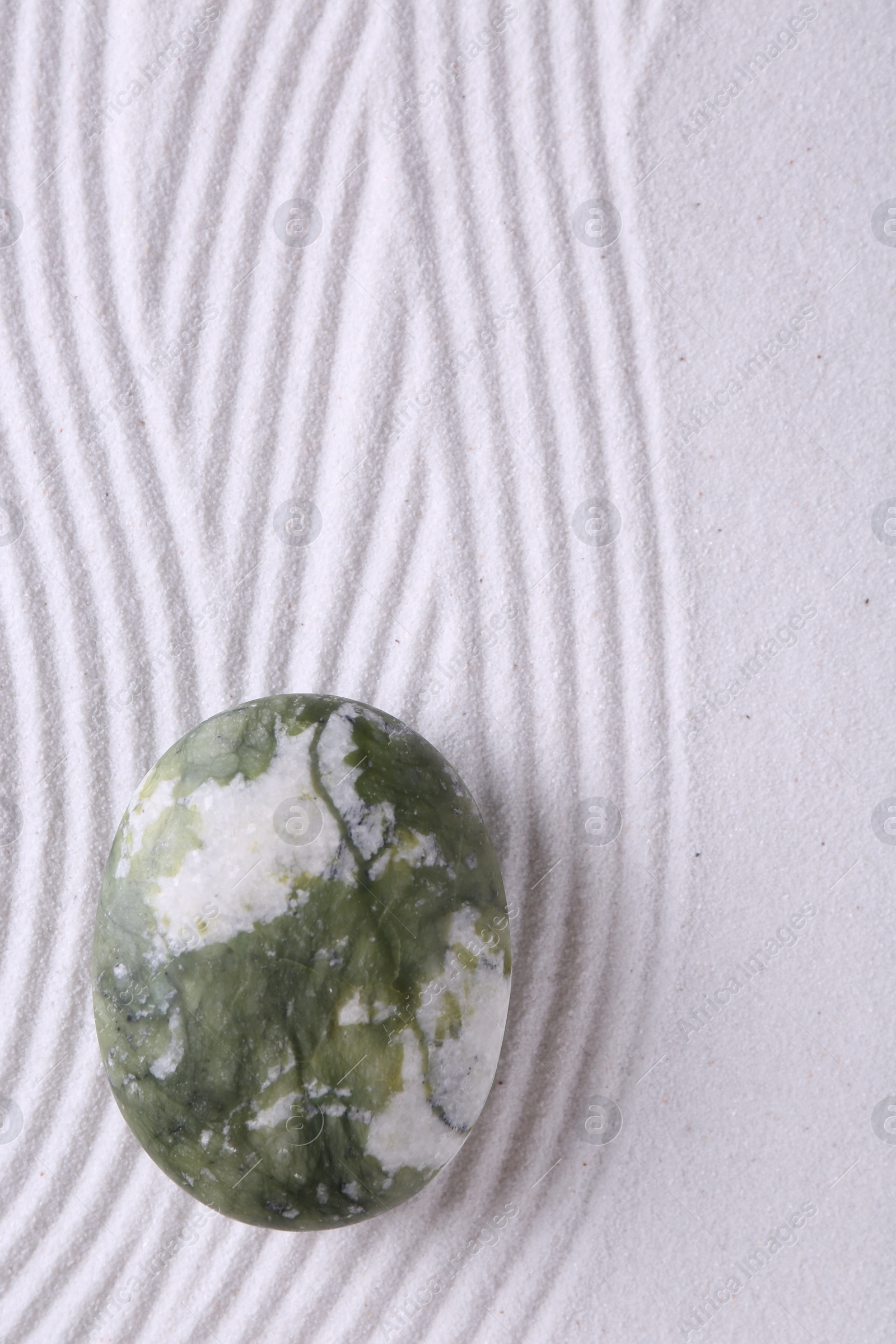 Photo of Zen concept. Stone and pattern on white sand, top view. Space for text