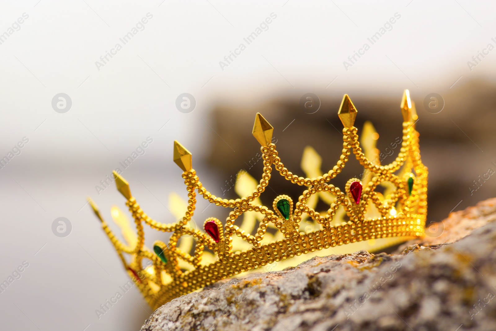 Photo of Beautiful golden crown on stone outdoors, closeup. Fantasy item