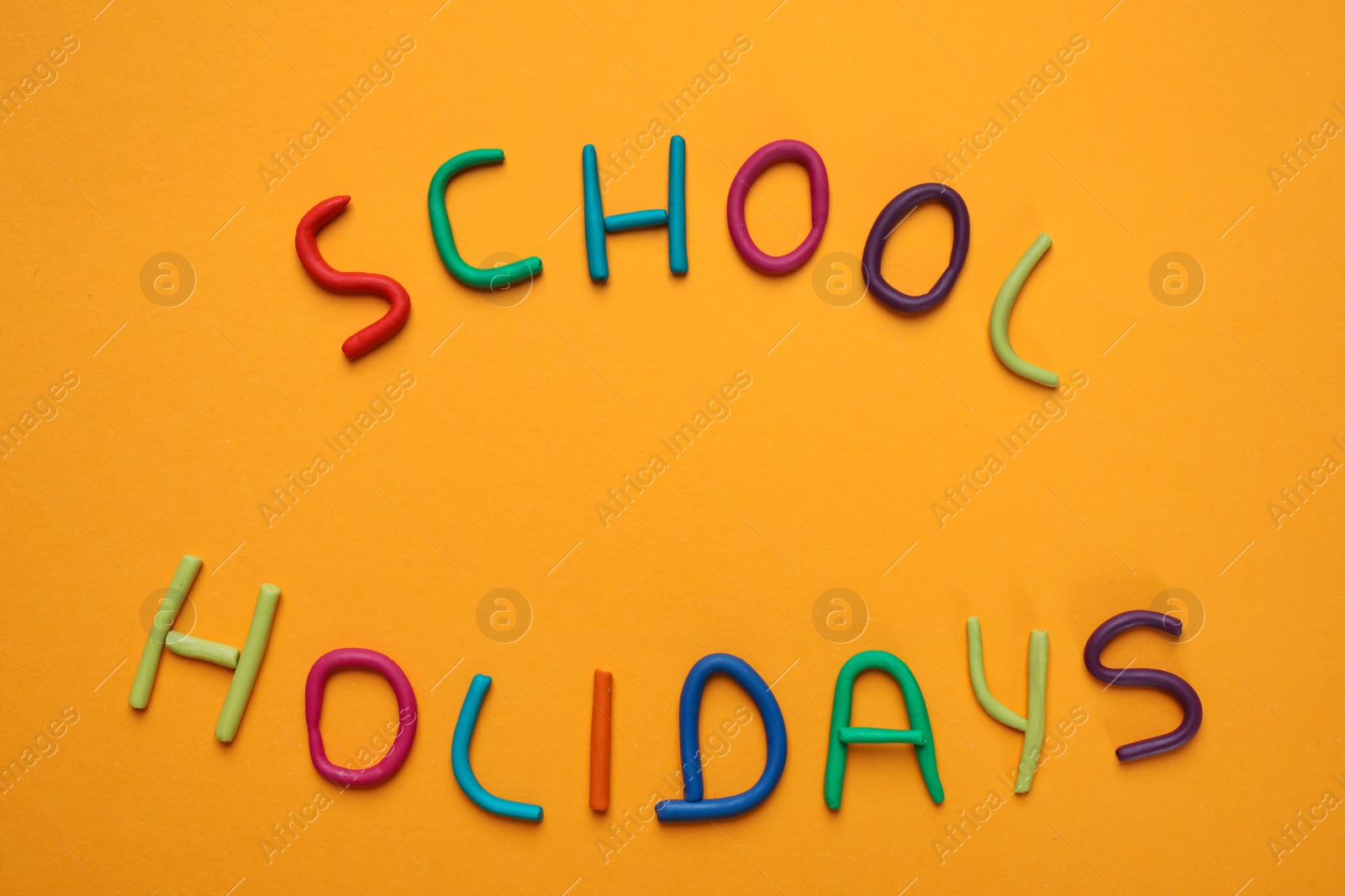 Photo of Phrase School Holidays made of modeling clay on orange background, top view