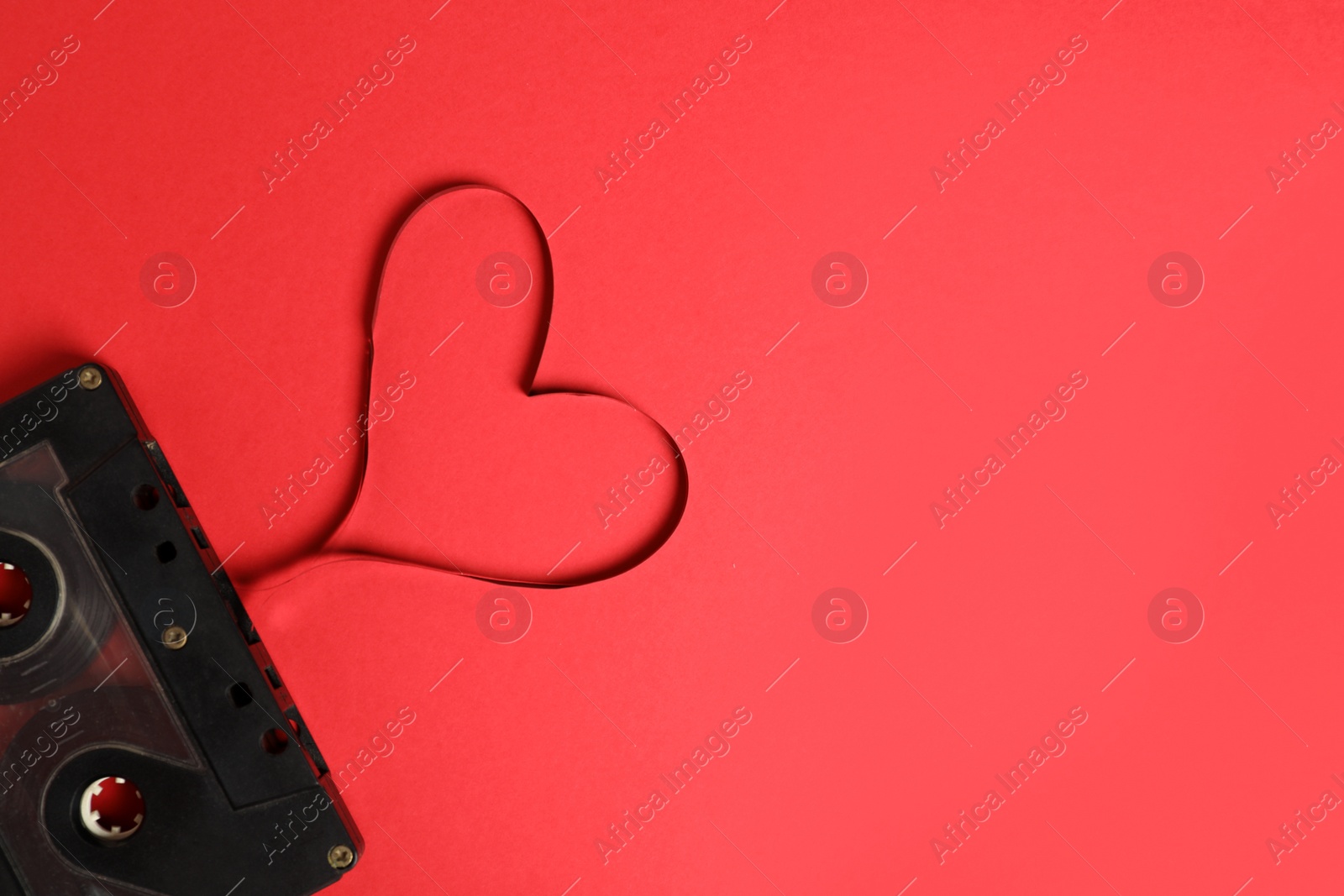 Photo of Top view of music cassette and heart made with tape on red background, space for text. Listening love song