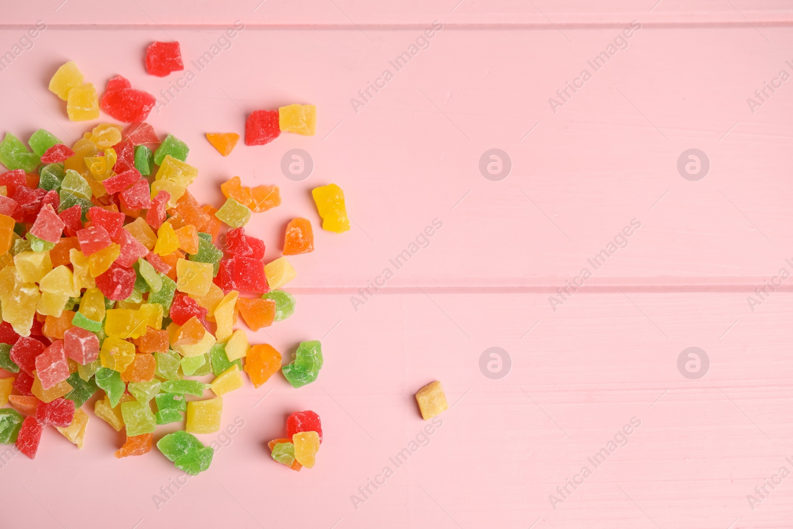 Photo of Mix of delicious candied fruits on pink wooden table, flat lay. Space for text