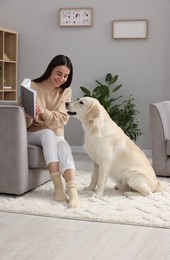 Woman reading book with cute Labrador Retriever dog at home. Adorable pet