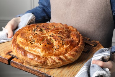 Woman holding tasty homemade pie indoors, closeup