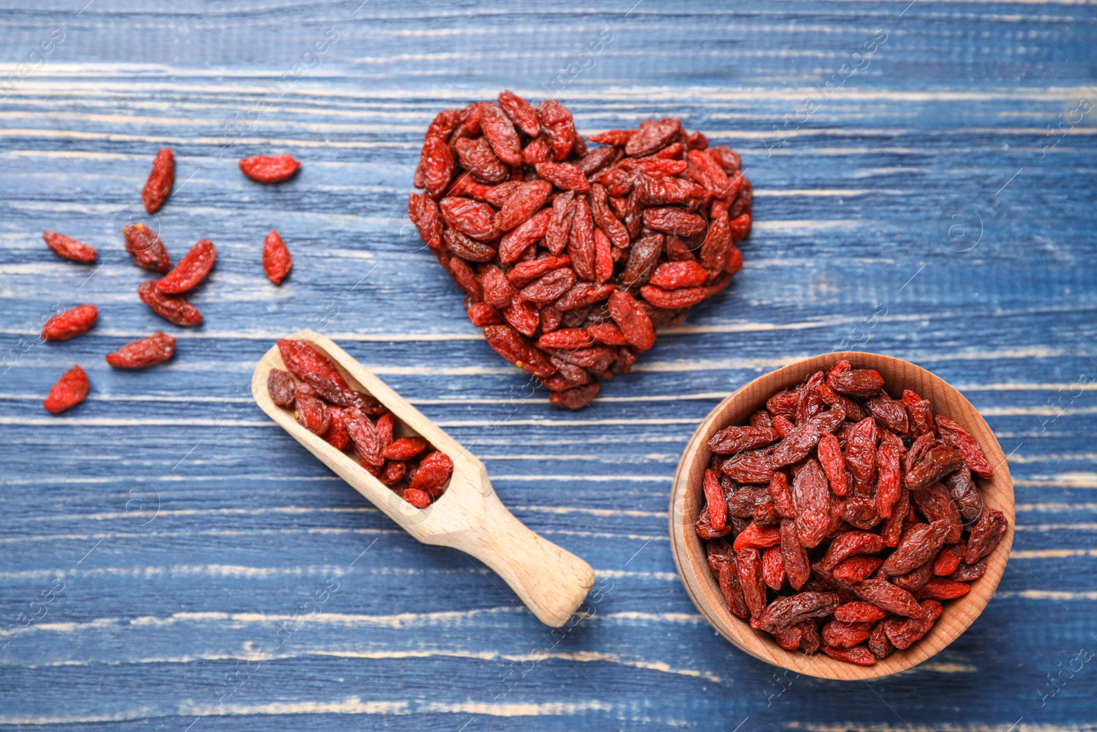 Photo of Flat lay composition with dry goji berries on blue wooden table
